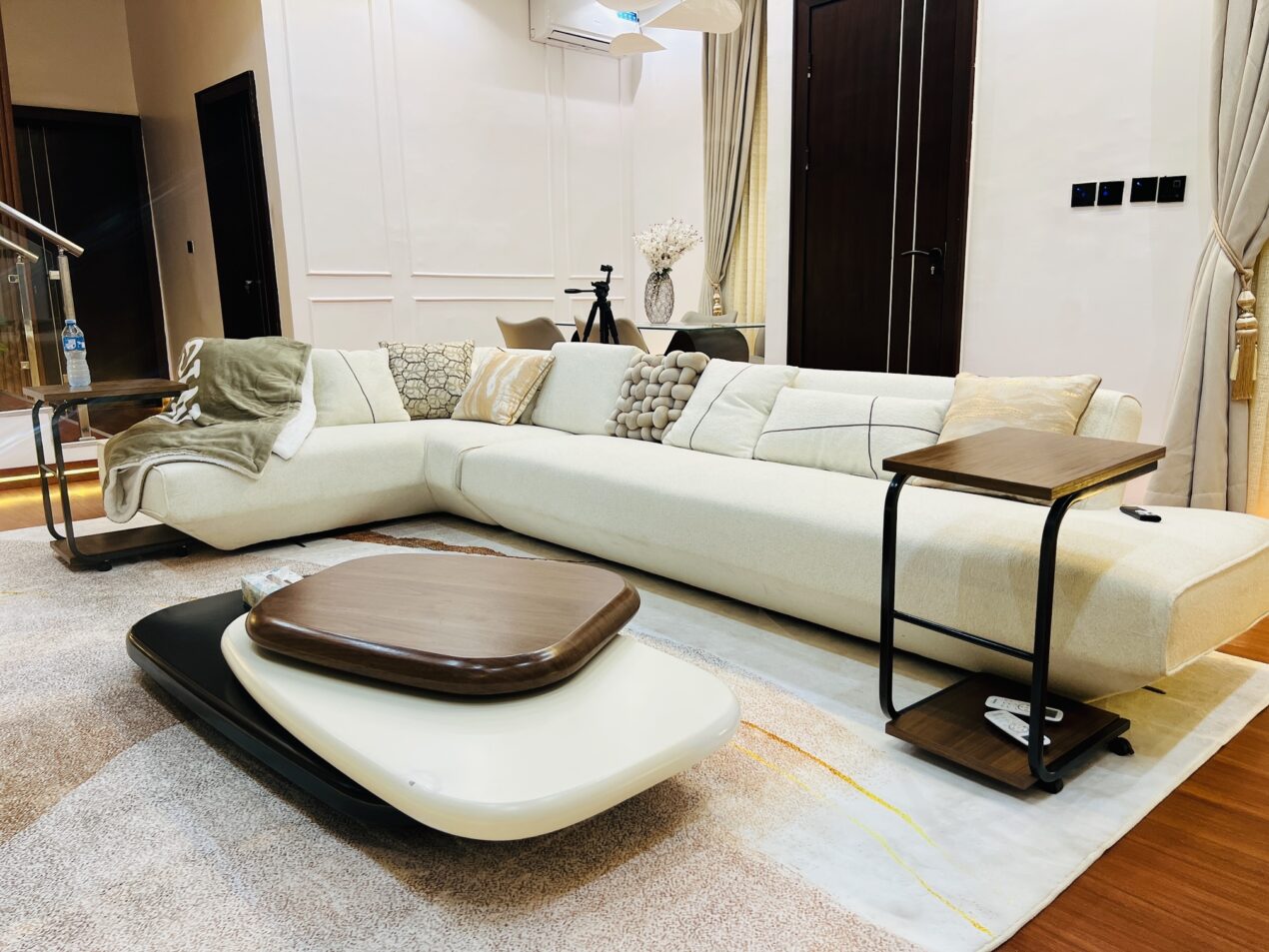 Living room with curved cream seating, marble-effect tables and layered neutral finishes.